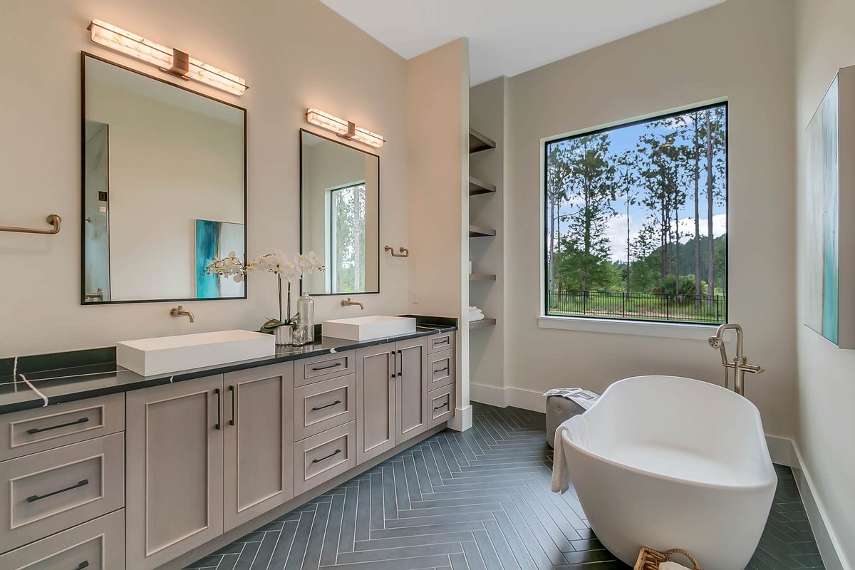 Master bathroom with herringbone porcelain floor, double vanity, and freestanding tub