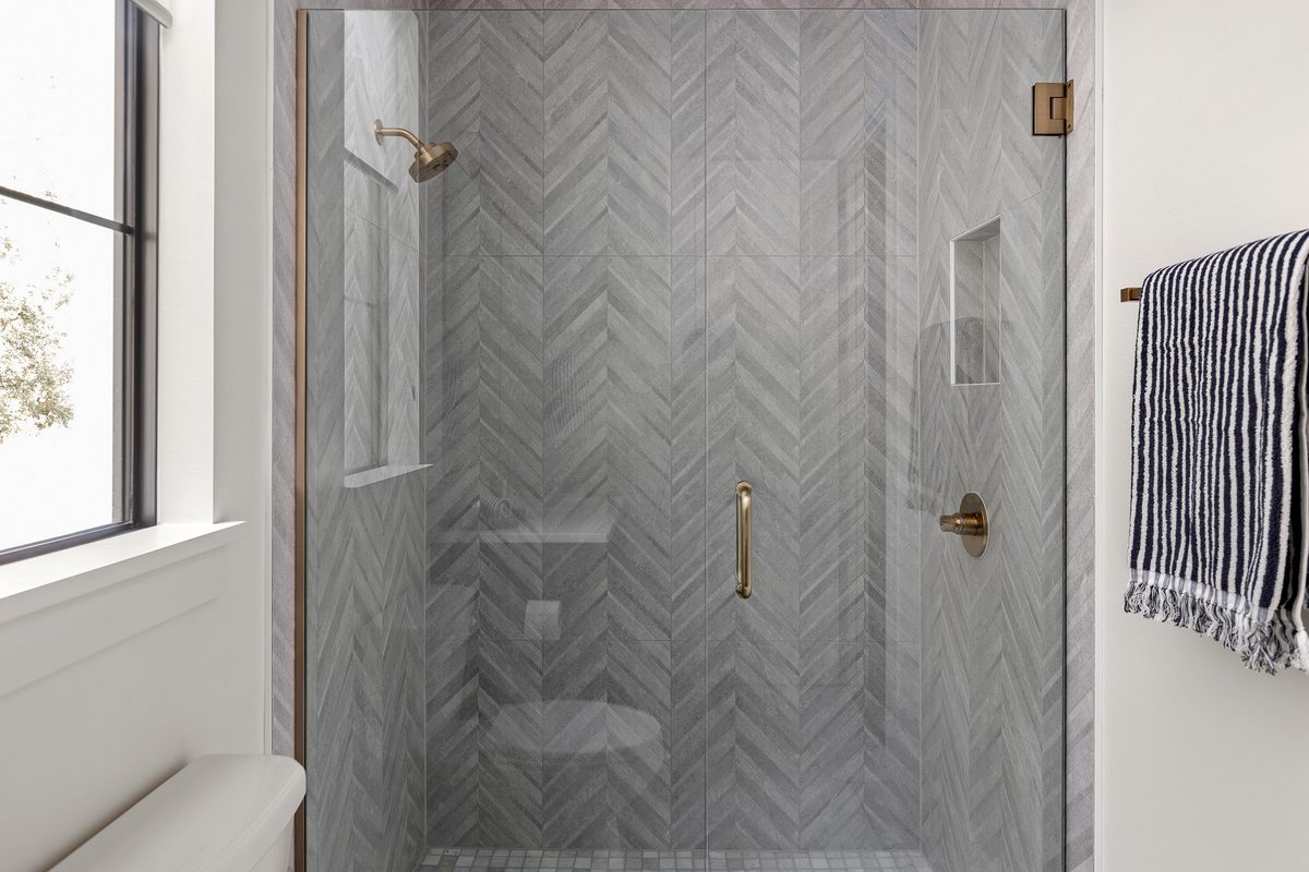 Glass-enclosed shower with grey chevron porcelain tile