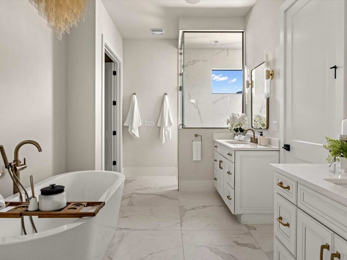 Bright master bath with marble-look porcelain floor and freestanding tub