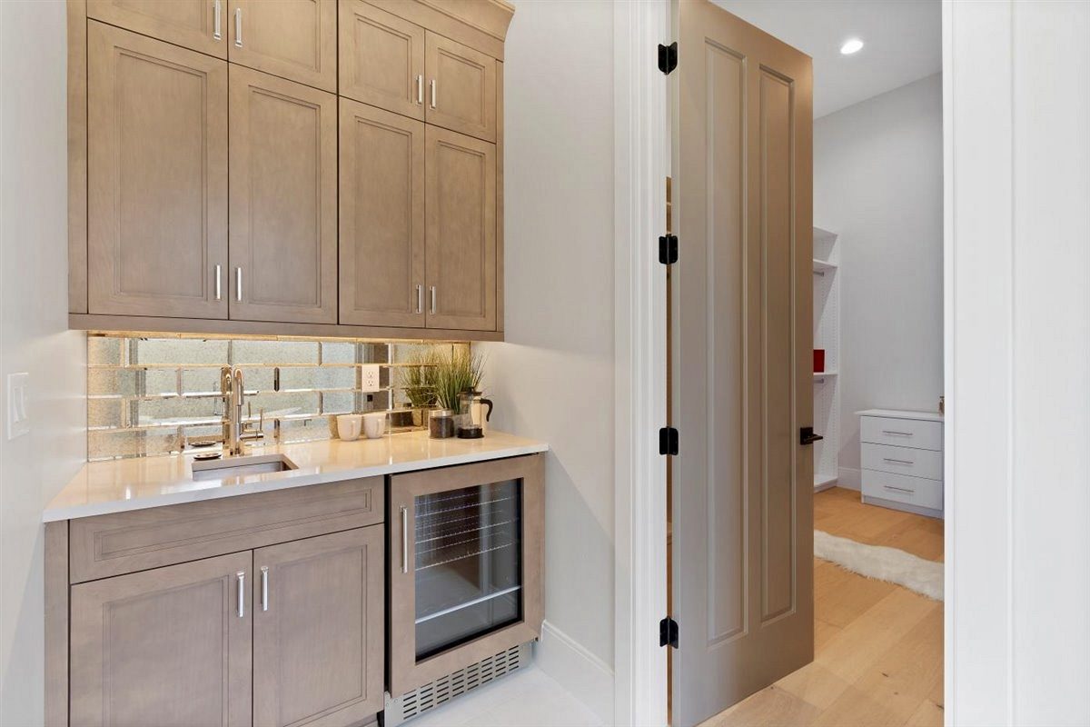 Antiqued mirror-finish tile backsplash above a wet bar with custom cabinetry